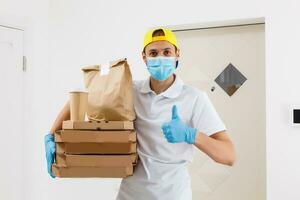 Contactless Pizza delivery. Pizza box. Delivery man holding cardboard boxes in medical rubber gloves and mask. Fast and free Delivery transport . Online shopping and Express delivery . Quarantine photo