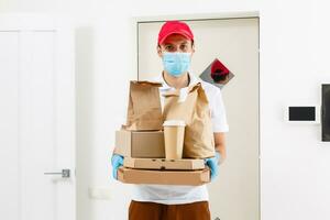 Courier in protective mask and medical gloves delivers takeaway food. Delivery service under quarantine, disease outbreak, coronavirus covid-19 pandemic conditions. photo