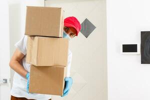 A man a medical mask and blue rubber gloves with a box, a parcel in his hands. Food delivery during the quarantine of the coronavirus pandemic. Home delivery, online order. Online shopping . photo