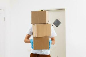 A man a medical mask and blue rubber gloves with a box, a parcel in his hands. Food delivery during the quarantine of the coronavirus pandemic. Home delivery, online order. Online shopping . photo