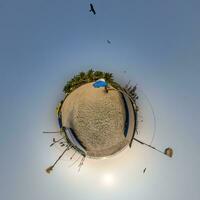 coconut trees in jungle in Indian tropic village on sea shore with fisher boat on little planet in evening sky, transformation of spherical 360 panorama. photo