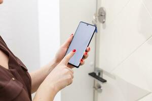 smart house, home automation, device with app icons. Woman uses smartphone with smarthome security app to unlock the door of house. photo