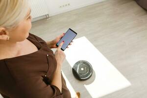 Hand holding smart phone and charged wirelessly device in background at modern domestic room, indoors. Concept advanced technology, vertical photo