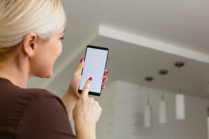 Smart Home Woman Controlling Lights With App On His Phone photo