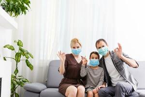 Happy family wearing face masks in a videoconference at home photo