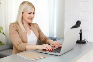 Portrait of happy skilled middle aged woman life coach, business consultant, psychologist or medical advisor smiling joyfully at camera, working on laptop, enjoying her job, helping people online photo