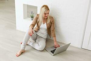 Ecommerce woman. Young female using computer for online shopping, sitting on the floor photo