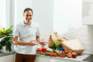 Man with fresh products at table indoors, closeup. Food delivery service photo