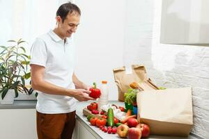 Man with fresh products at table indoors, closeup. Food delivery service photo