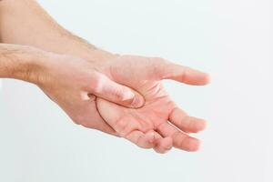 hombre con doloroso y enconado gota en su mano alrededor el pulgar área. foto