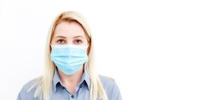 Close up of woman wearing protective mask, looking aside at copy space, isolated on blue background. Flu, allergy, protection against virus, coronavirus pandemic - covid-19. Medical mask advertising photo