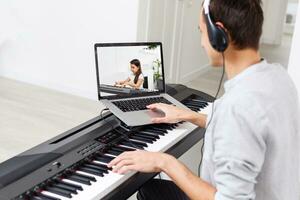 A man learning to play piano online with a computer staying at home. Concepts of self taught, staying at home and working online photo