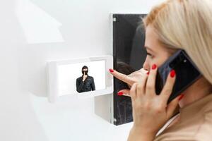 Woman inside home answering security phone photo