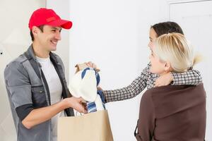 mother and daughter receive order from delivery man, delivery of toys and goods for children at home photo