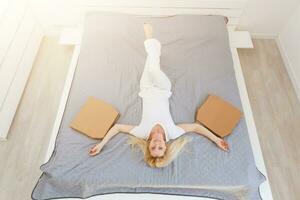 Portrait of a cute girl wearing a pajamas, lying on the bed and pizza from the box. Girl is resting on a holiday,lying on the bed and eating a delicious pizza.View from above.Copyspace photo