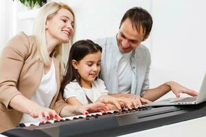 Happy family, mother, father and daughter playing piano at home, concept for family relationship. music school and music family. photo