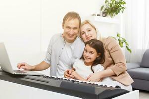 family plays the digital piano at home, learning online, family rest during quarantine, self-isolation, online education concept. support for loved ones concept photo