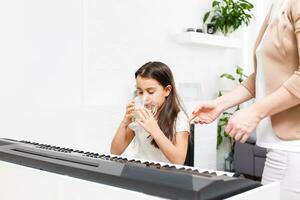 girl playing the piano at home, learning online photo