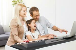 family plays the digital piano at home, learning online, family rest during quarantine, self-isolation, online education concept. support for loved ones concept photo