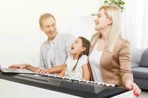 Happy family, mother, father and daughter playing piano at home, concept for family relationship. music school and music family. photo