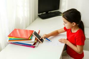 Distance learning online education, little girl writes formulas photo