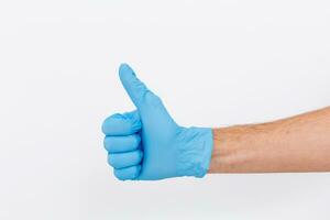 Hand of surgeon in blue medical glove showing Ok sign, isolated on a white background photo