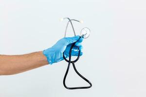 Close up of female doctor's hand in blue sterilized surgical glove with stethoscope against white background photo