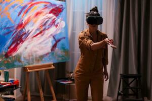 Painter wearing virtual reality headset in art studio. Modern artwork paint on canvas, creative, contemporary and successful fine art artist drawing masterpiece photo