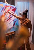 Painter using virtual reality headset and creating a masterpiece on large canvas. Modern artwork paint on canvas, creative, contemporary and successful fine art artist drawing masterpiece photo