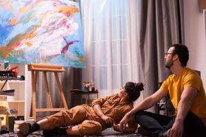 Painter and is partner having a conversation about abstract painting on large canvas. Modern artwork paint on canvas, creative, contemporary and successful fine art artist drawing masterpiece photo