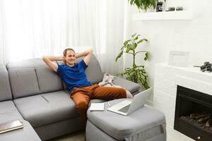 Happy smiling young man watching and working on computer laptop at home photo