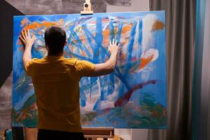 Artist painting with fingertips on large canvas in art studio. Modern artwork paint on canvas, creative, contemporary and successful fine art artist drawing masterpiece photo
