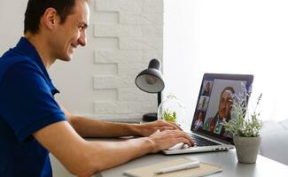 Man having video chat with doctor on laptop at home photo