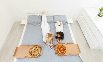 young mother and her little daughter eating pizza and having fun photo