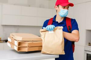 Deliveryman with protective medical mask holding pizza box - days of viruses and pandemic, food delivery to your home. photo