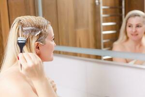 A middle-aged woman dyes her hair at home, indoors photo