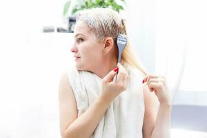 Hair dyeing in the domestic bathroom. One woman only photo