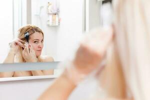 A middle-aged woman dyes her hair at home, indoors photo