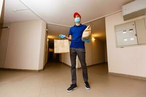 Delivery man holding cardboard boxes in rubber gloves and mask. Online shopping and Express delivery photo