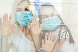 Family, standing behind the window, at home, quarantine due to coronavirus photo