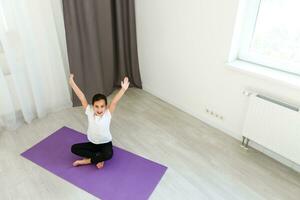 pequeño niña practicas yoga a hogar foto