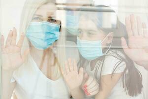 Family, standing behind the window, at home, quarantine due to coronavirus photo