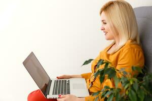 young beautiful smiling woman prints on the laptop - indoors photo