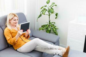 Woman using digital tablet on couch photo