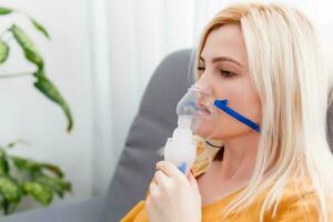 mujer hace inhalación nebulizador a hogar. participación un máscara nebulizador inhalando vapores rociar el medicación dentro tu livianos enfermo paciente. autotratamiento de el respiratorio tracto utilizando inhalación nebulizador foto