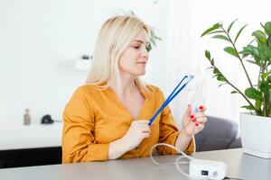 woman makes inhalation nebulizer at home. holding a mask nebulizer inhaling fumes spray the medication into your lungs sick patient. self-treatment of the respiratory tract using inhalation nebulizer photo