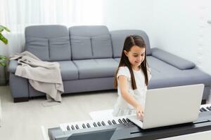 Pretty young musician playing classic digital piano at home during online class at home, social distance during quarantine, self-isolation, online education concept photo