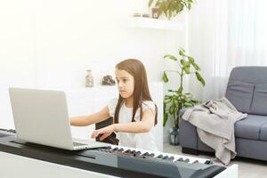 Pretty young musician playing classic digital piano at home during online class at home, social distance during quarantine, self-isolation, online education concept photo
