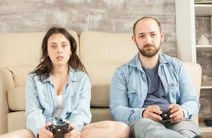 Focused young couple while playing video games using wireless controller. photo