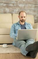 hombre trabajando en ordenador portátil sentado en vivo habitación alfombra. foto